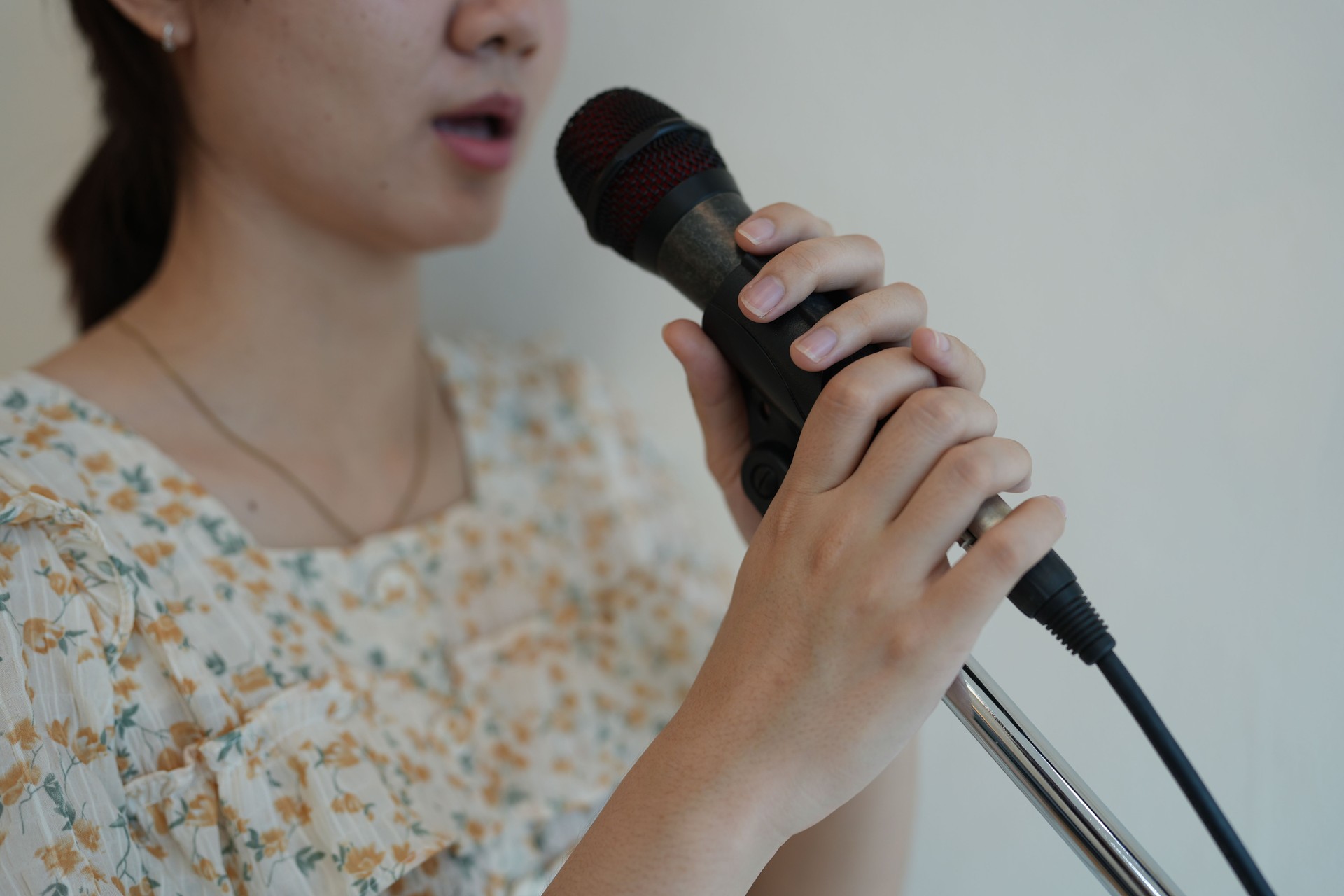 Young Woman Holding Microphone While Singing with Passion in a Bright and Inviting Space, Emphasizing Vocal Performance and Artistic Expression